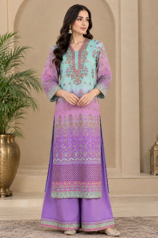A woman models a traditional three-piece Indian salwar kameez suit. The set features a light blue and purple gradient kurta with intricate gold and pink embroidery, paired with matching wide-leg trousers in purple and a coordinating pink border.