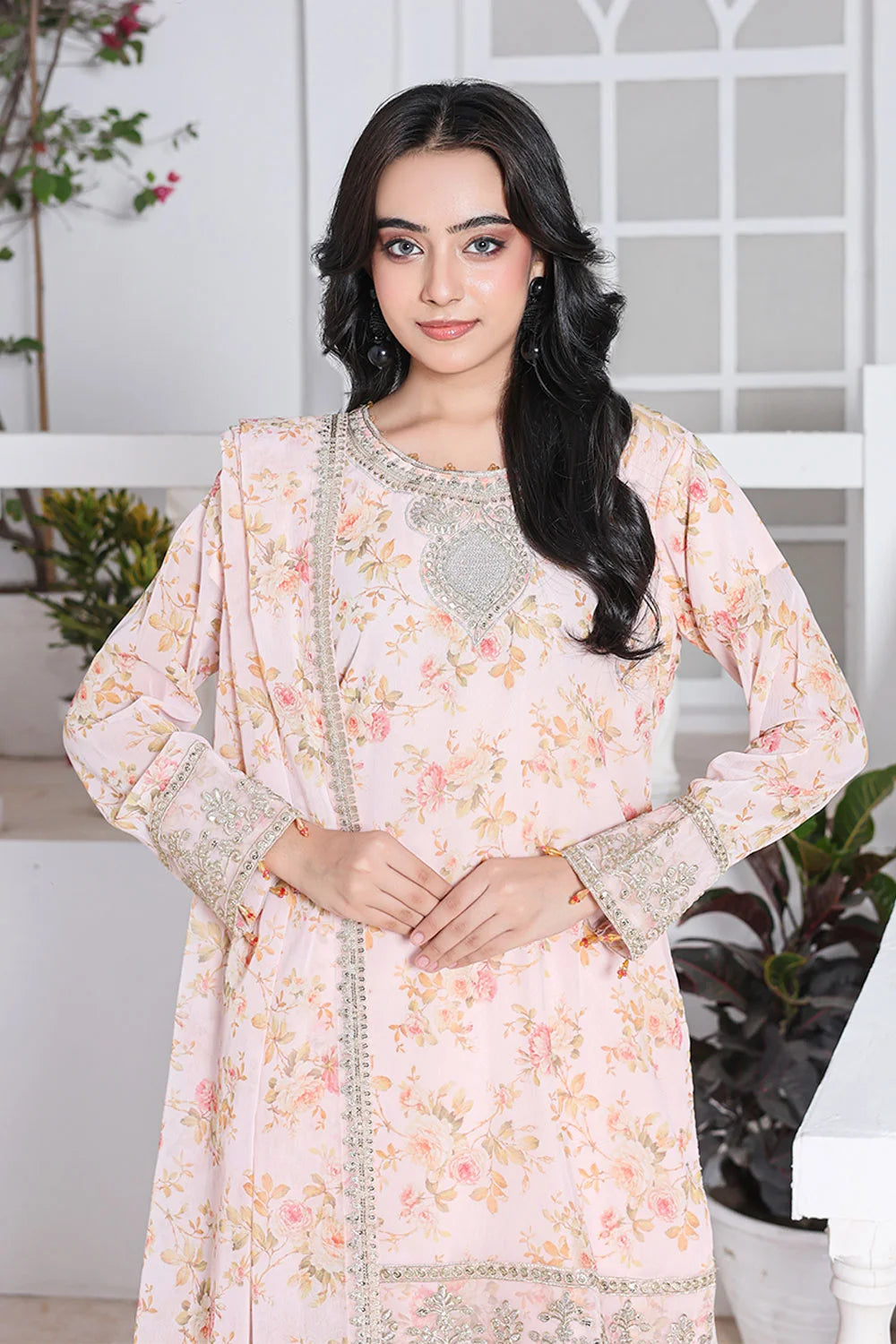 Woman wearing a floral dress with intricate patterns in a bright indoor setting