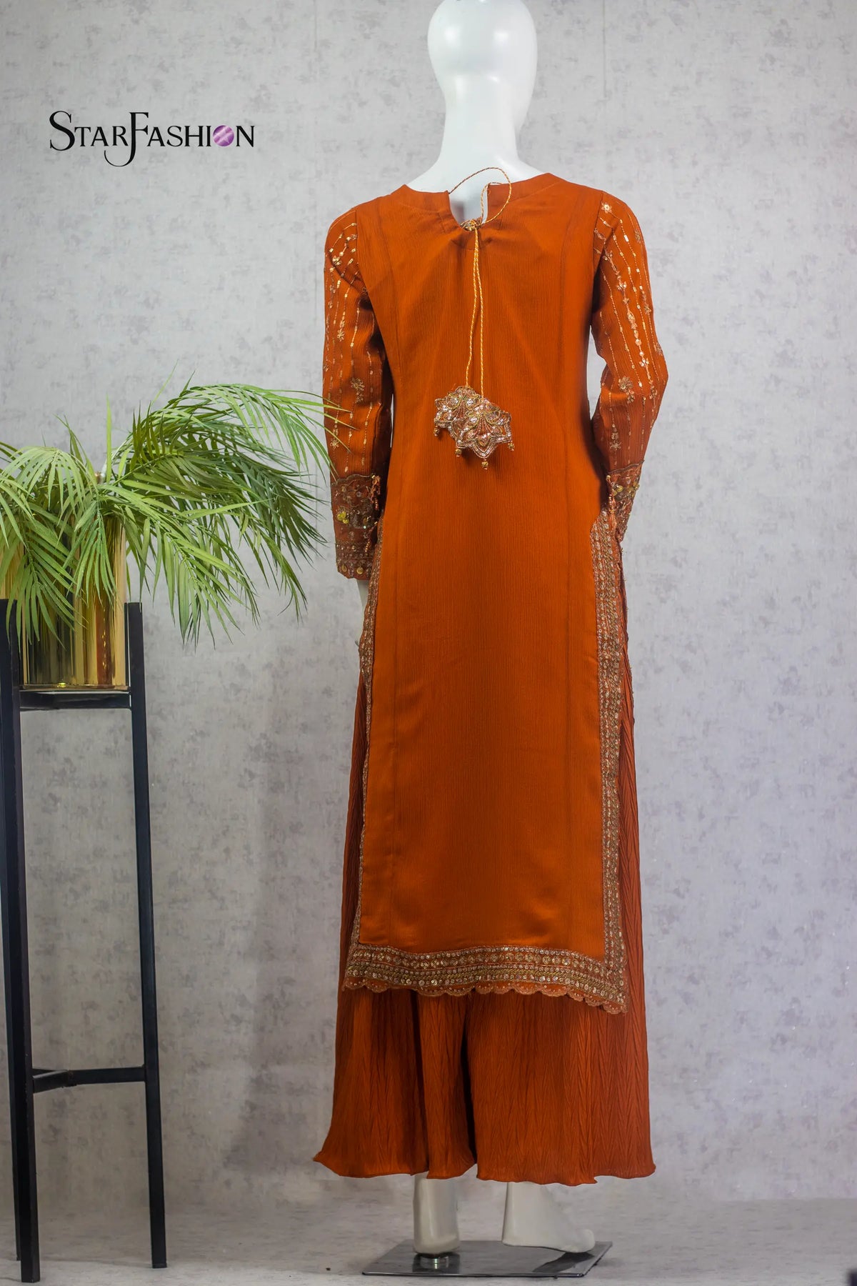 Orange traditional outfit on a mannequin with 'StarFashion' branding, against a neutral background.