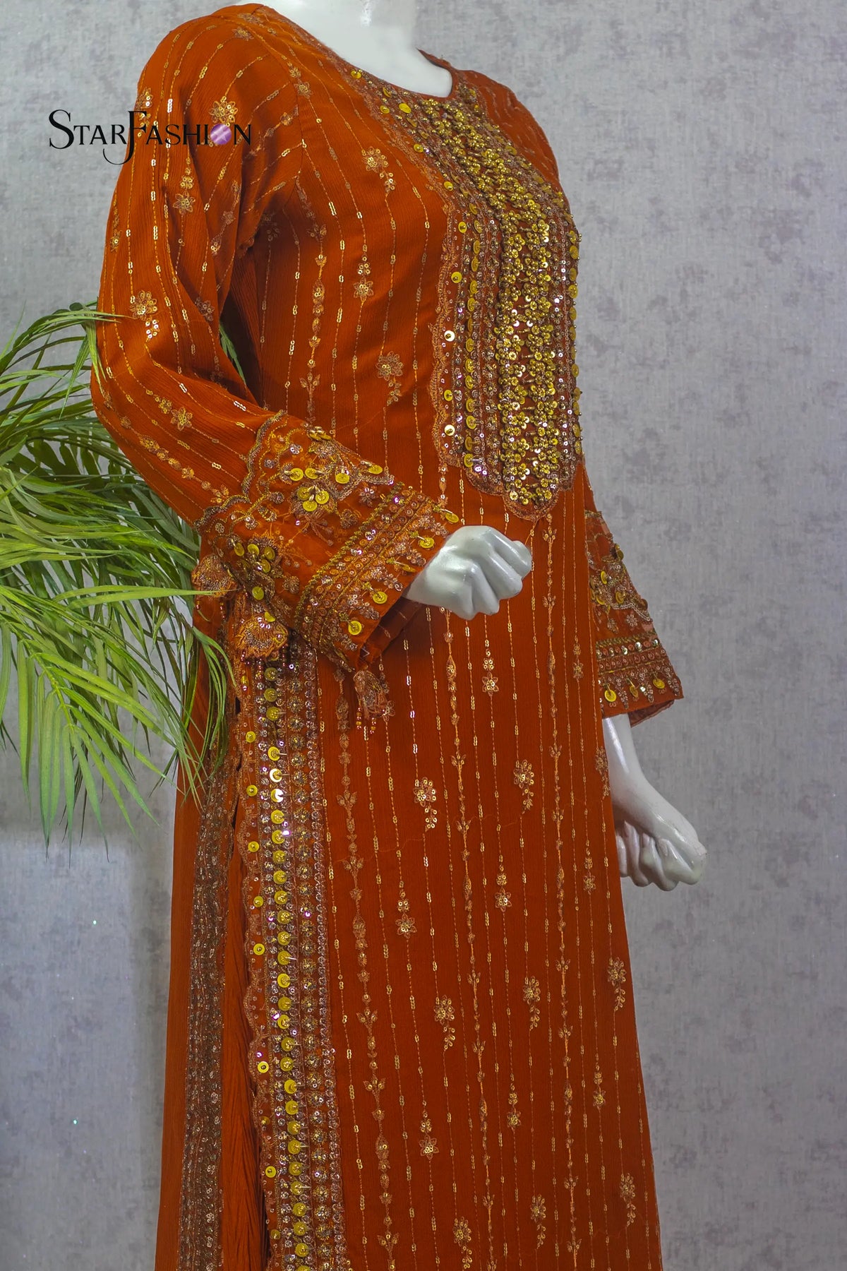 Orange embroidered dress on a mannequin with a gray background