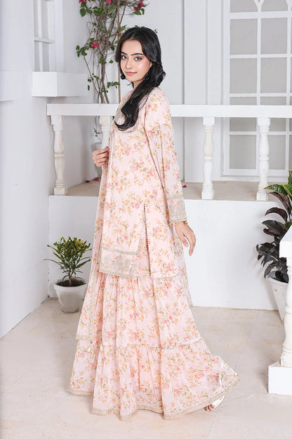 Woman in a floral dress standing in a bright, minimalistic room with plants.